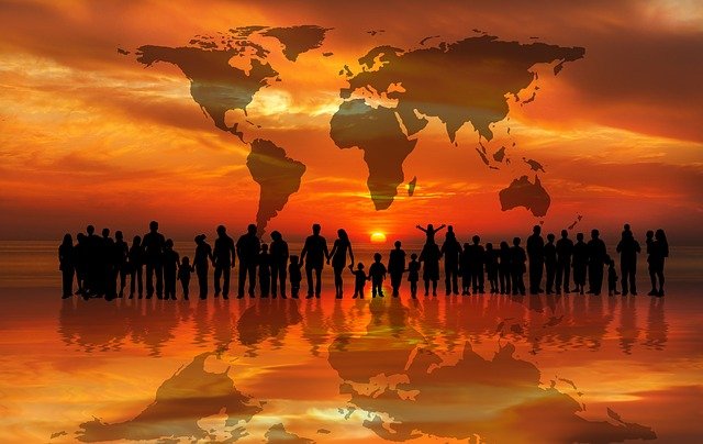groupe de personnes sur une plage au couché du soleil avec la map du monde au dessus d'enx